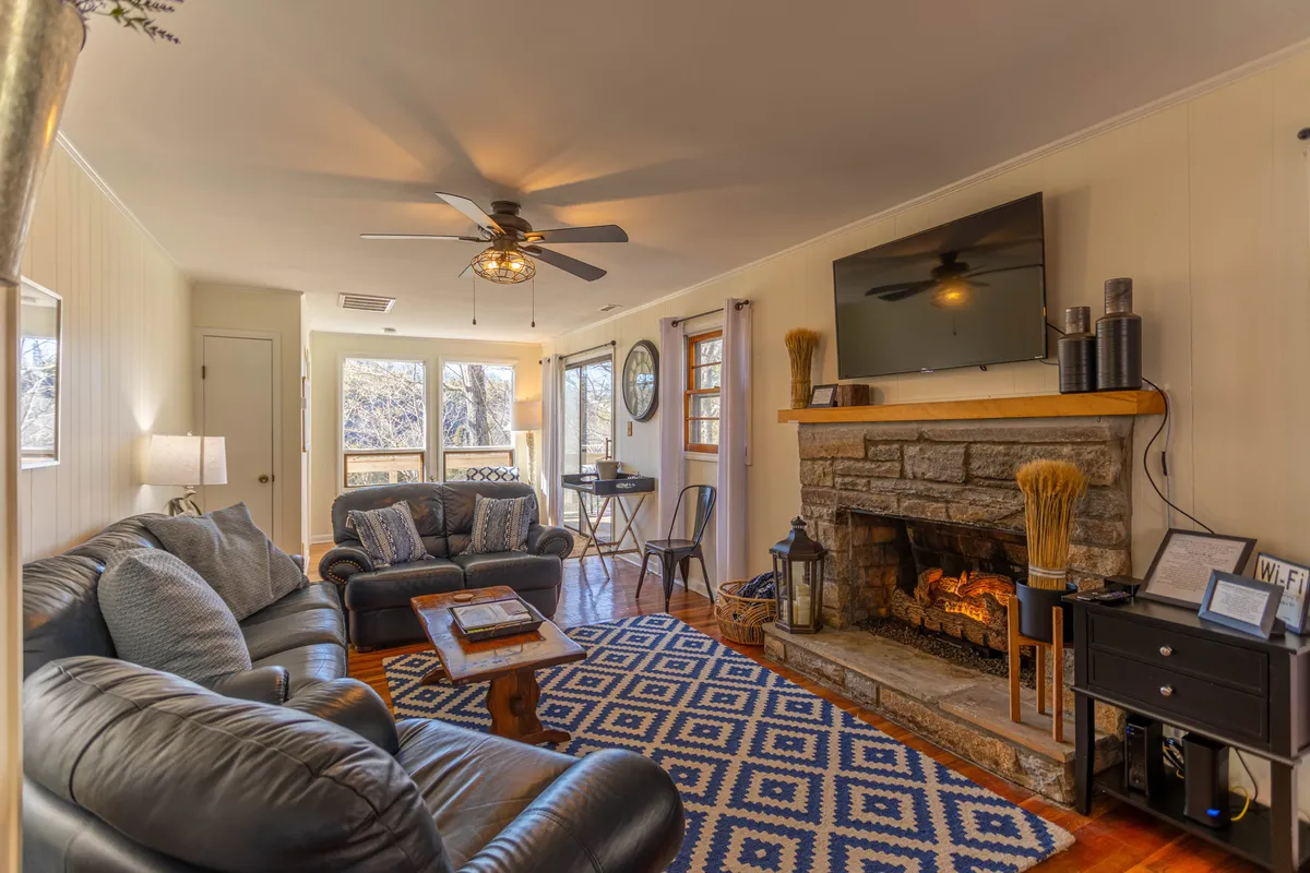 A warm, inviting room featuring a fireplace, comfortable sofa, rug, and a TV creates an ideal setting for cozy evenings, lively game nights, or simply relaxing after a day of fun. The fire adds a sense of comfort and makes the den suitable year-round.