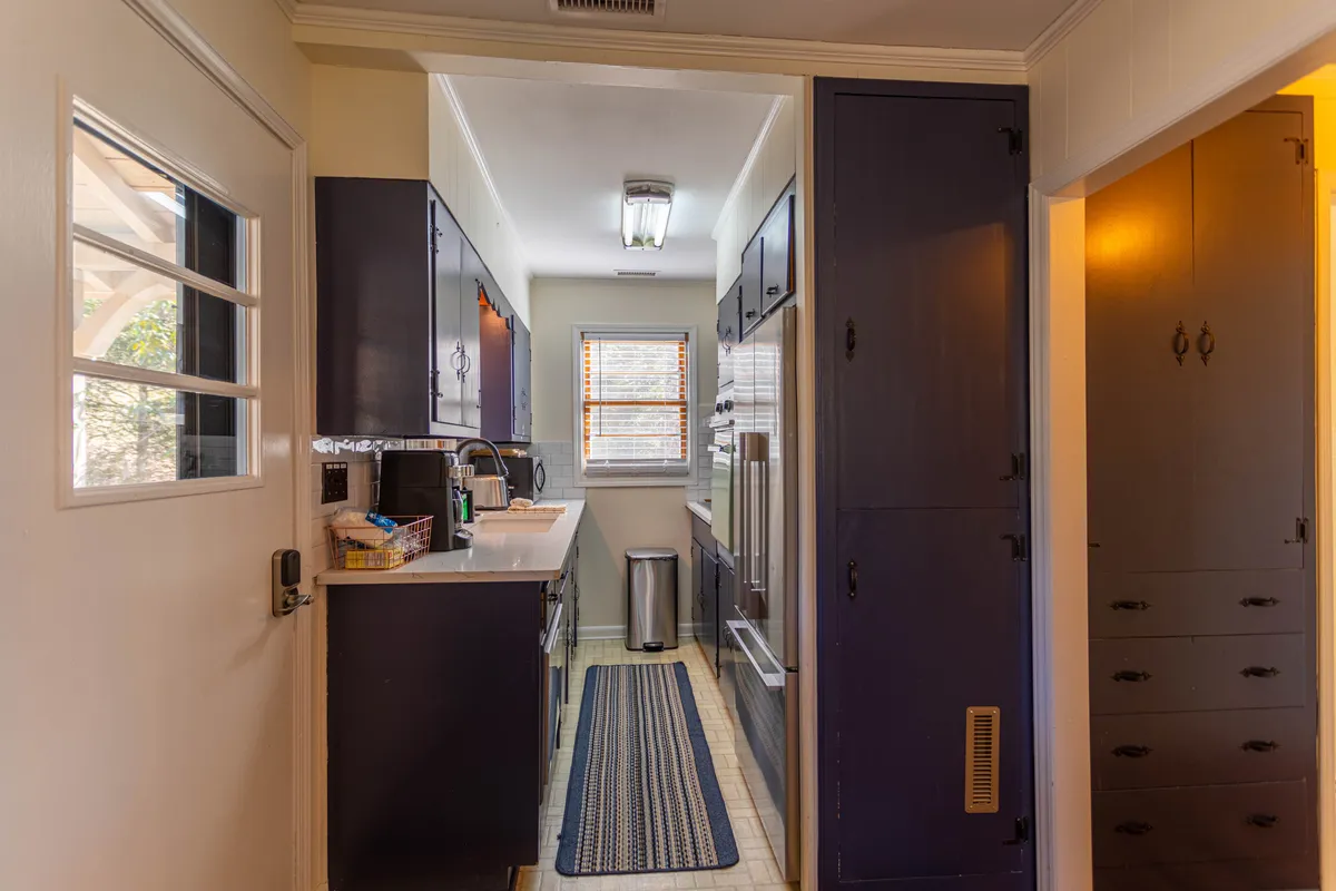 A bright, welcoming kitchen with a central sink, classic oven, spacious counters, ample cabinets, and a window letting in natural light. The space feels ready for meal preparation, baking, or gathering with friends and family.