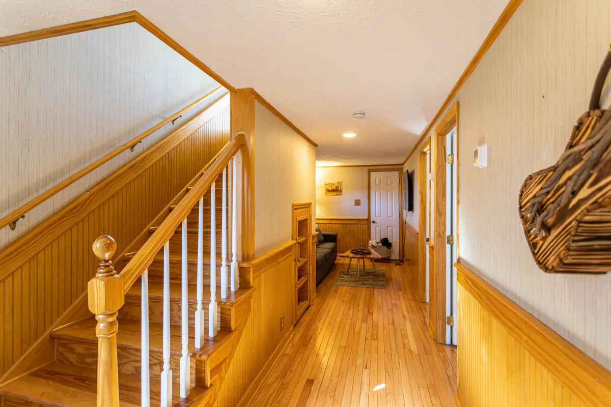 A warm, inviting living space with a visible staircase, comfortable seating area, and wooden furniture, creating an atmosphere made for relaxing or reconnecting after a day of activities.