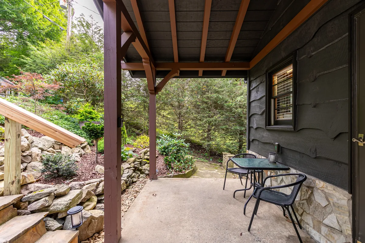 Two black chairs are arranged along a stone pathway amid lush greenery and wooden steps, offering a serene setting for morning coffee or quiet conversation outdoors.